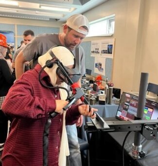 A student tries out a welding simulator at the June "Trades Promoting Trades" event.